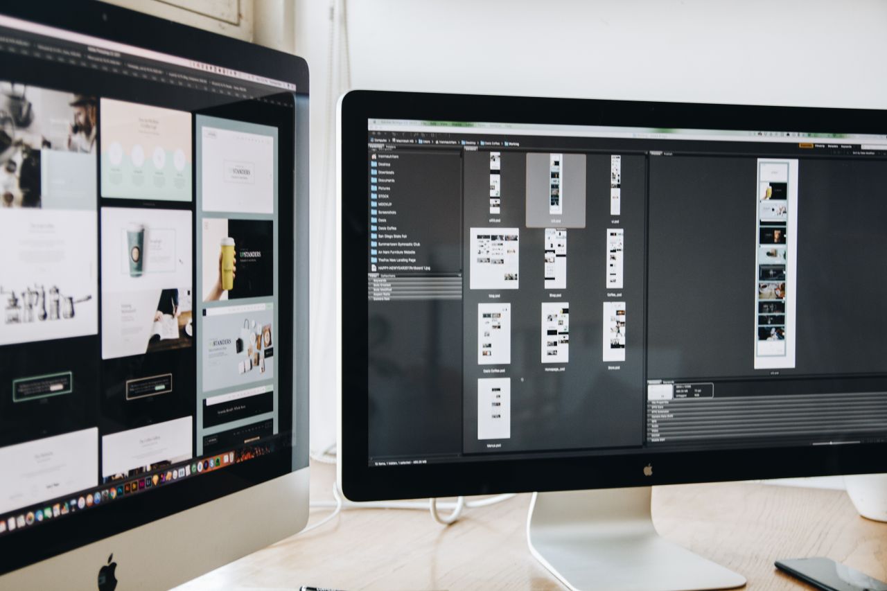 Un espace de travail moderne avec deux écrans d’ordinateur affichant des projets de web design, mettant en avant la technologie et la productivité.